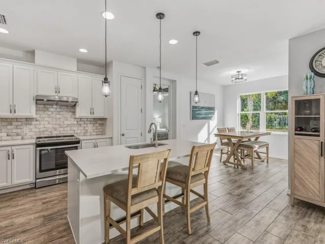 a kitchen with stainless steel appliances granite countertop a stove a kitchen island a dining table and chairs with wooden floor