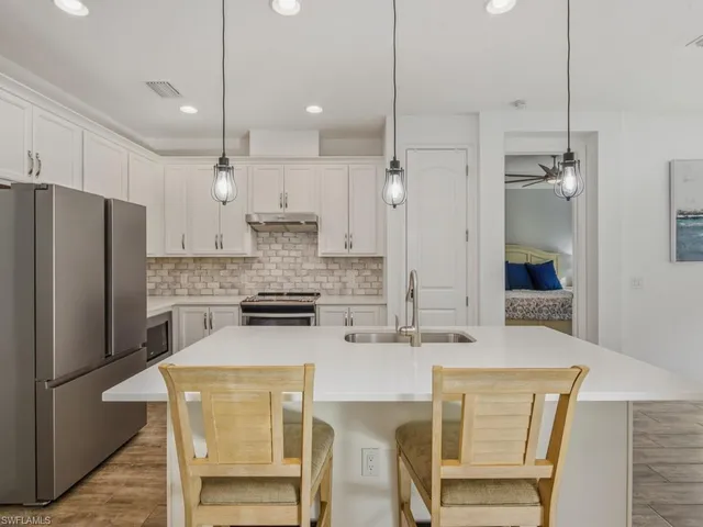 a kitchen with stainless steel appliances granite countertop a kitchen island a stove a refrigerator a oven a sink with a dining table and chairs