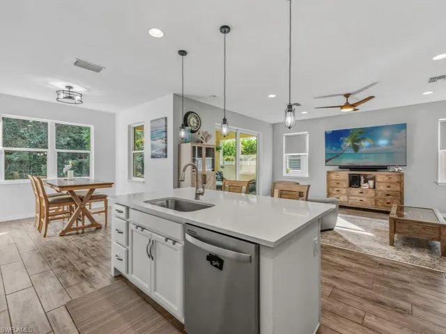 a open kitchen with stainless steel appliances granite countertop a stove a sink a dining table and chairs with wooden floor