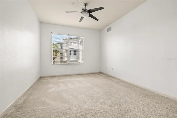 an empty room with windows and fan