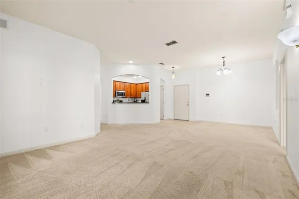 a view of an empty room and a kitchen