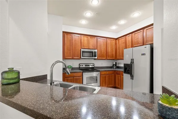 a kitchen with stainless steel appliances granite countertop a refrigerator a stove top oven a sink and dishwasher