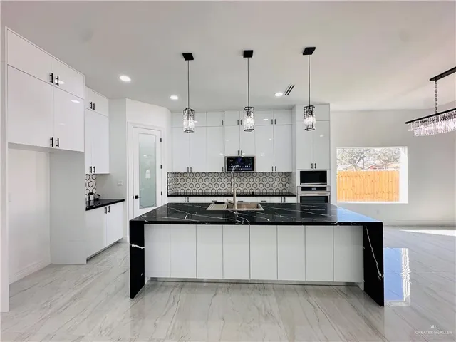 a kitchen with granite countertop a sink a stove and cabinets
