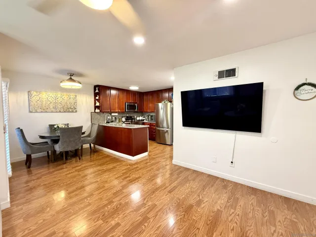 a living room with stainless steel appliances kitchen island granite countertop furniture and a flat screen tv