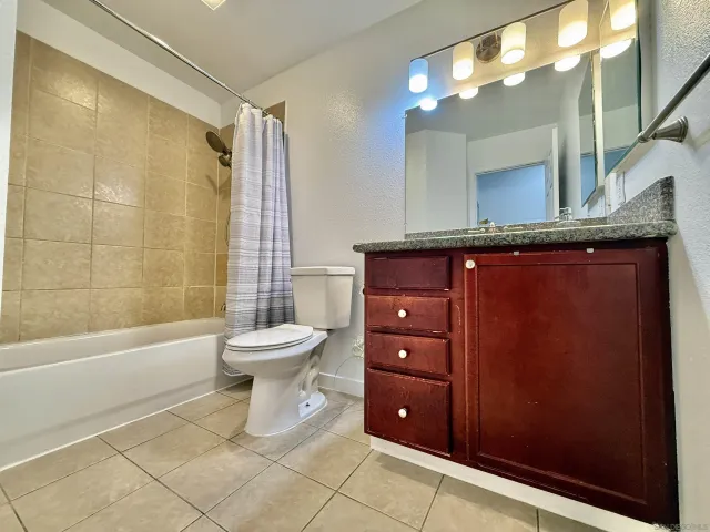 a bathroom with a granite countertop sink toilet a mirror a vanity and bathtub