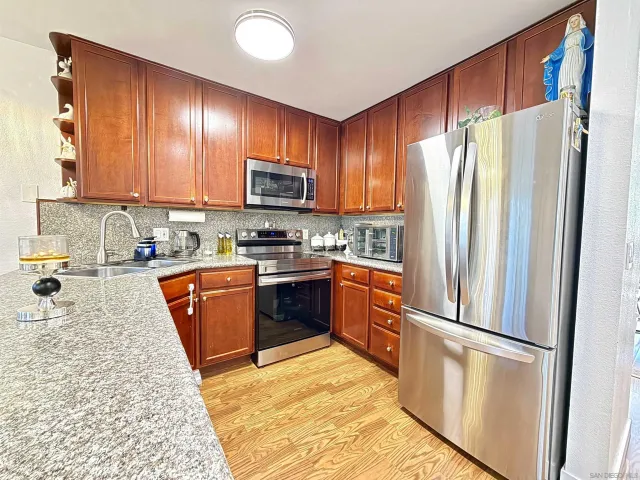 a kitchen with stainless steel appliances granite countertop a refrigerator stove microwave and sink