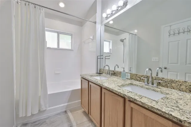a bathroom with a granite countertop sink a mirror and a bathtub