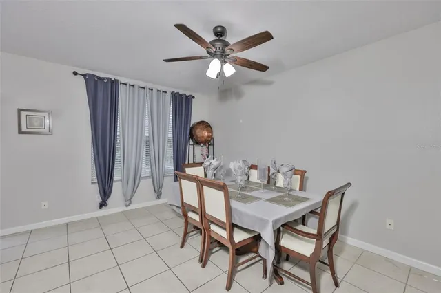 a dining room with furniture and a chandelier fan