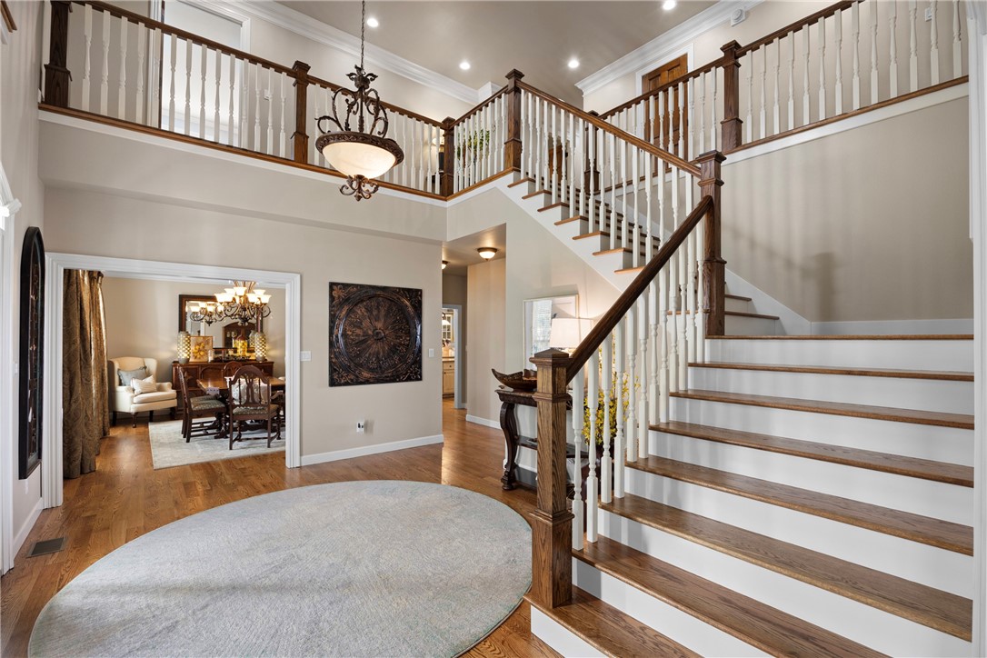 Stairway with a high ceiling, crown molding, wood finished floors, and hanging lights