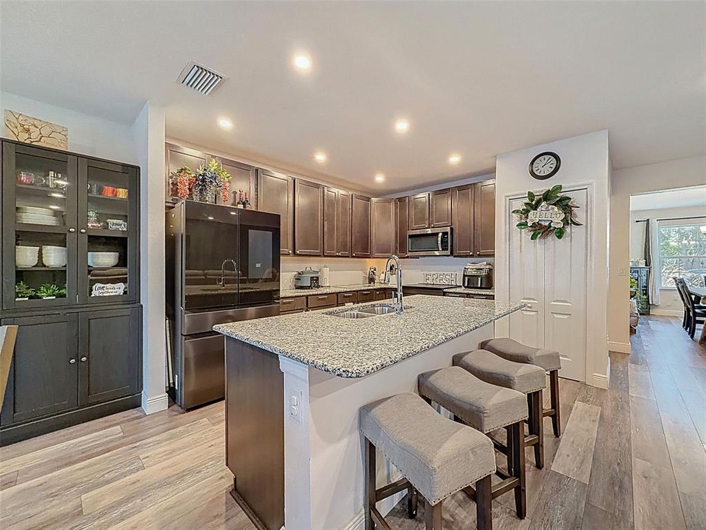 237 Leafy Way Avenue Spring Hill, FL 34606 - Photo 19 of 68 a kitchen with stainless steel appliances granite countertop a refrigerator oven a sink a dining table and chairs with wooden floor