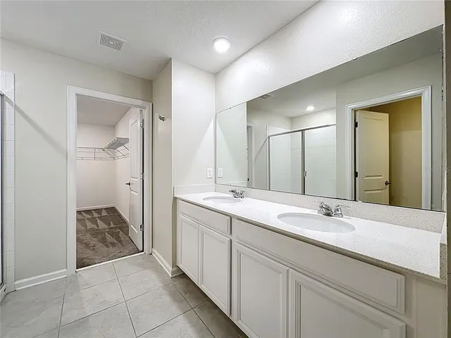 a spacious bathroom with a double vanity sink mirror and shower