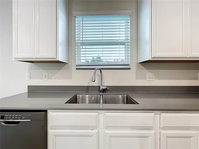 a kitchen with granite countertop white cabinets and a sink