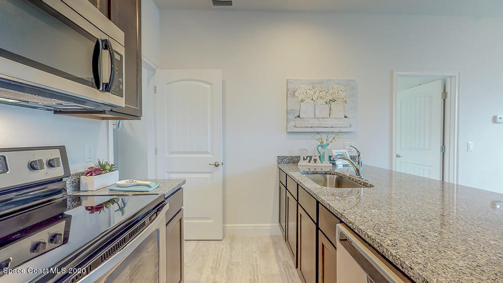 572 Corbin Circle Southwest Palm Bay, FL 32908 - Photo 25 of 32 a kitchen with stainless steel appliances granite countertop a sink stove and cabinets