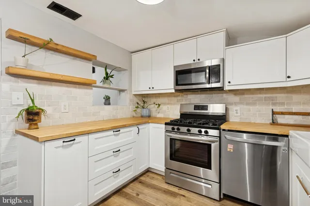 a kitchen with white cabinets stainless steel appliances and sink