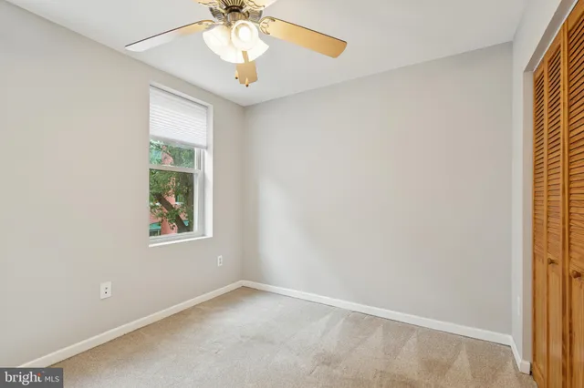an empty room with windows and fan