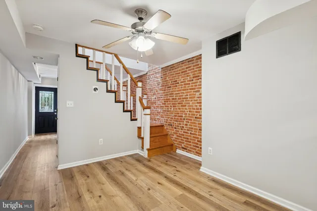 a view of an empty room with stairs and wooden floor