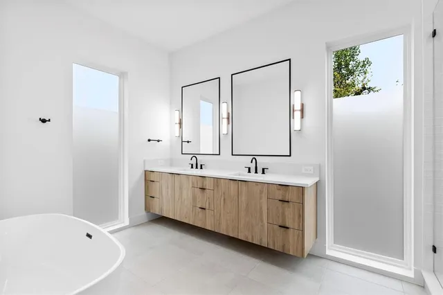 a bathroom with a double vanity sink mirror and bathtub