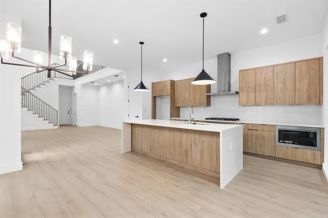 a open kitchen with stainless steel appliances granite countertop a sink a oven a stove and a wooden floors