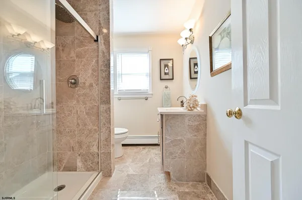 a bathroom with a granite countertop sink a toilet and shower