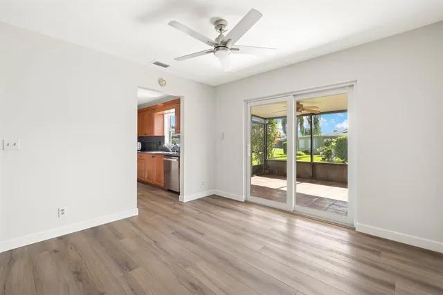 an empty room with wooden floor a ceiling fan and windows