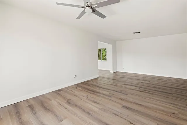 a view of an empty room with wooden floor and a window