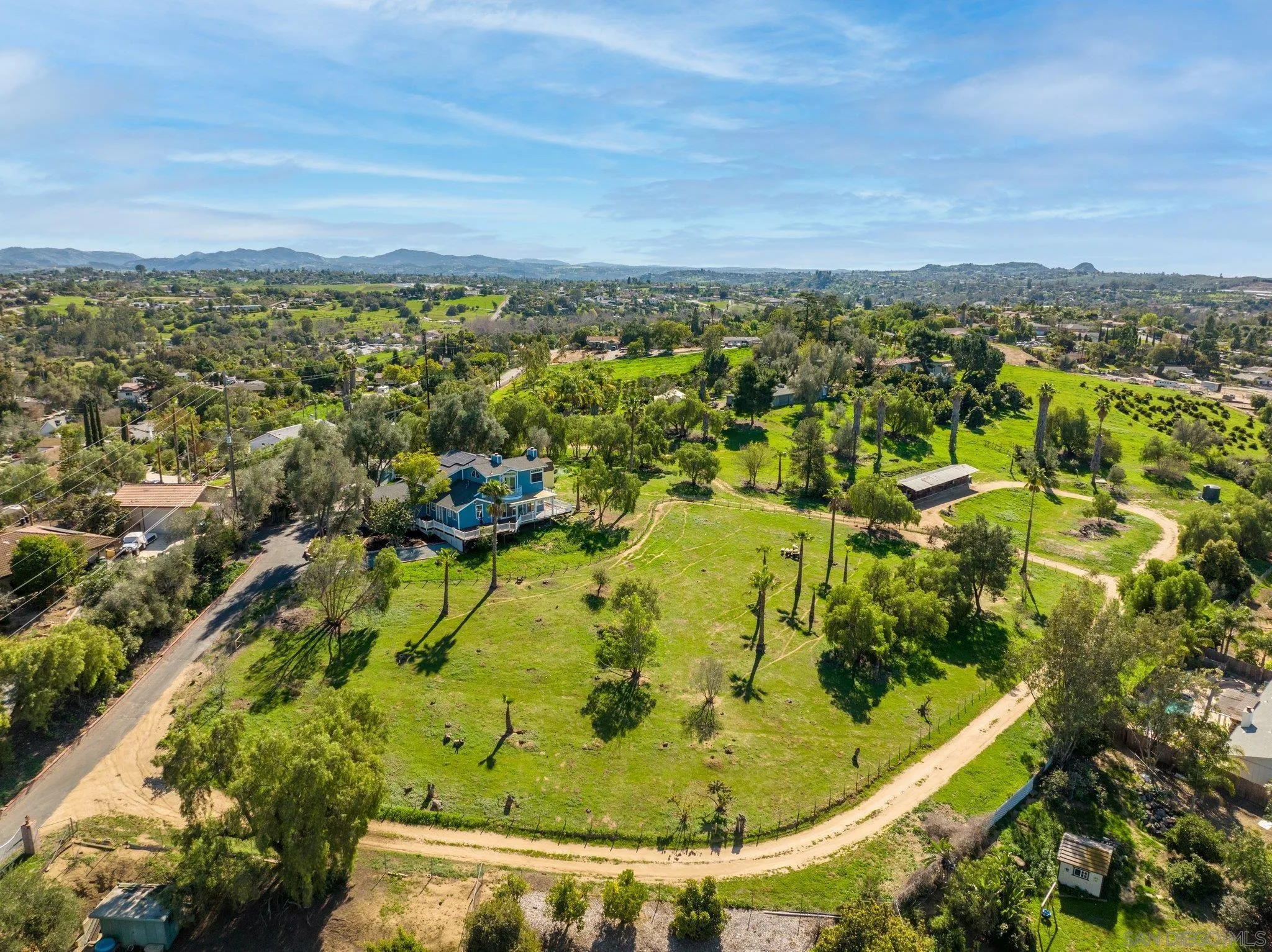 an aerial view of residential houses with outdoor space and trees