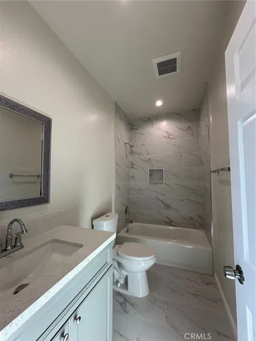 a bathroom with a granite countertop sink a toilet and shower