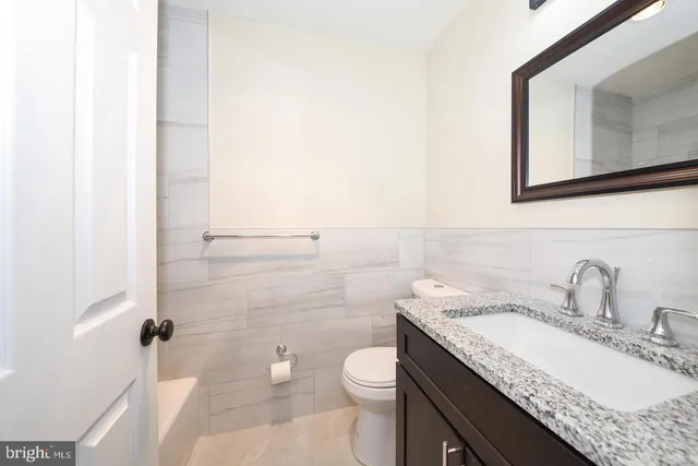 a bathroom with a granite countertop sink toilet and mirror