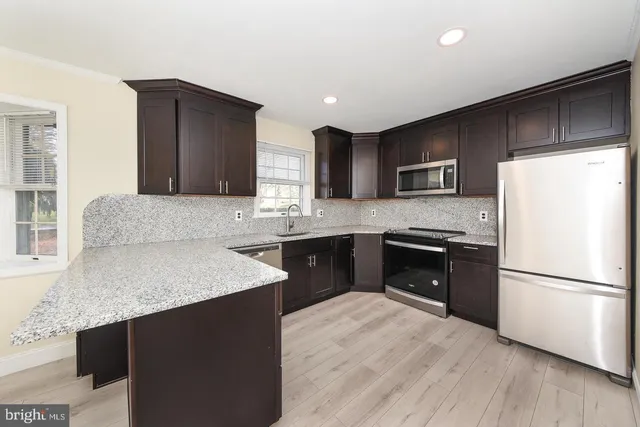 a kitchen with stainless steel appliances granite countertop a refrigerator a sink a stove a microwave and cabinets