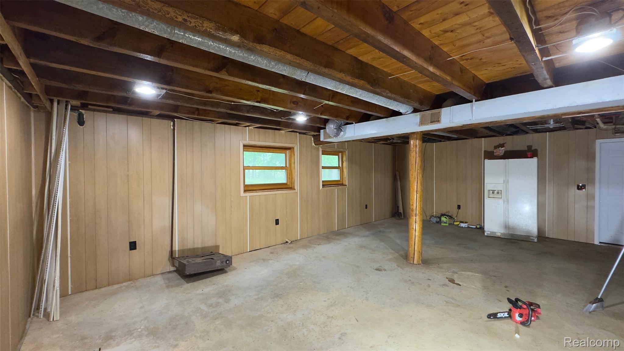 2608 East Sutton Road Metamora, MI 48455 - Photo 32 of 64 Spacious basement area featuring paneling, exposed wood ceiling beams, two windows, concrete flooring, and recessed lighting