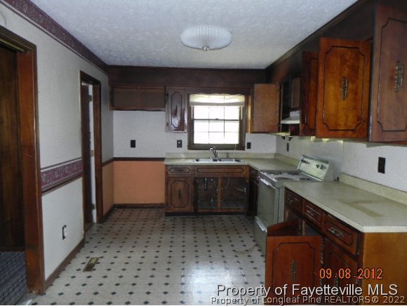 3910 Turnpike Road Raeford, NC 28376 - Photo 8 of 14 a kitchen with a sink a stove cabinets and a window