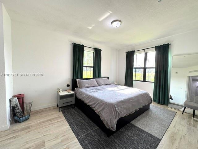 15650 Southwest 136th Street, Unit 101 Miami, FL 33196 - Photo 6 of 16 a bedroom with a bed a mirror and a large window