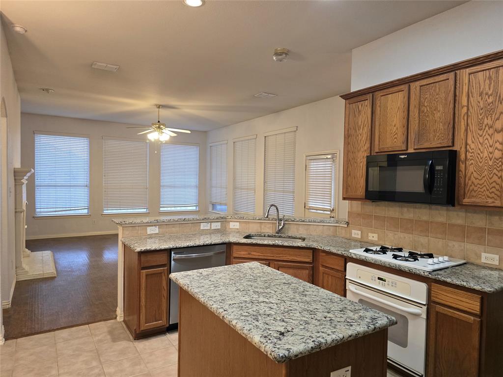 100 Bryan Street Prosper, TX 75078 - Photo 3 of 18 a kitchen with stainless steel appliances granite countertop a stove a sink and a microwave