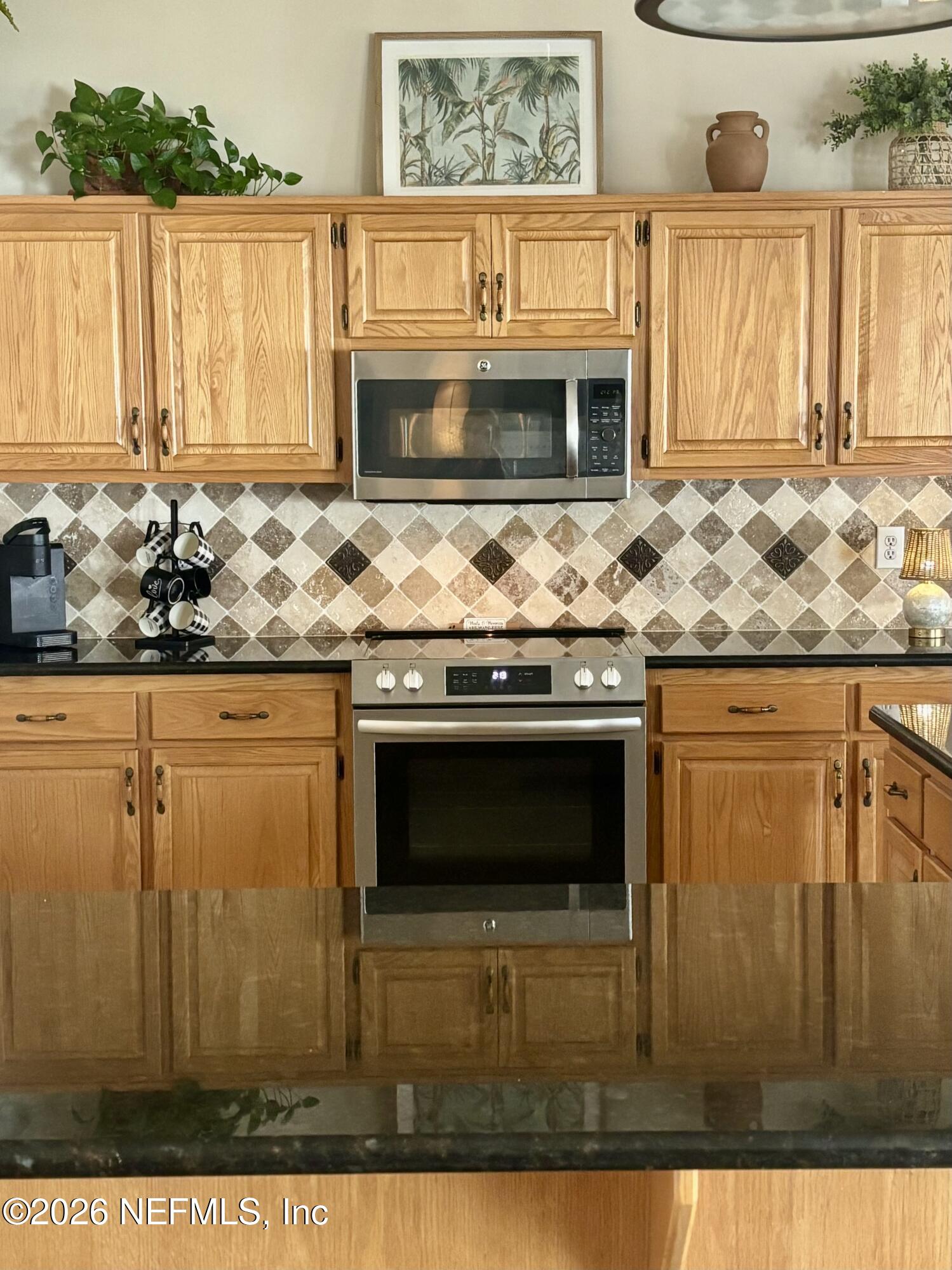 1168 Copper Gate Place Macclenny, FL 32063 - Photo 14 of 51 a kitchen with granite countertop a stove top oven microwave and cabinets