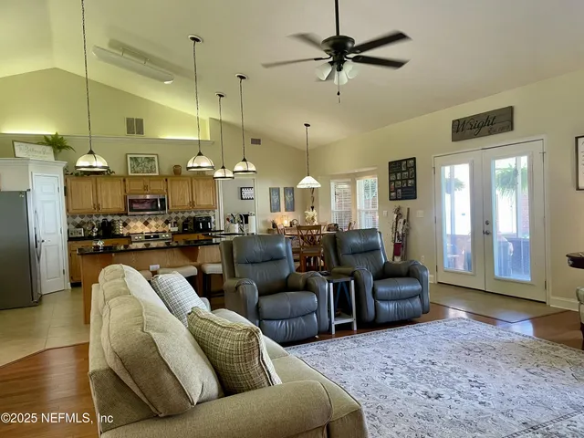 a living room with furniture kitchen view and a chandelier