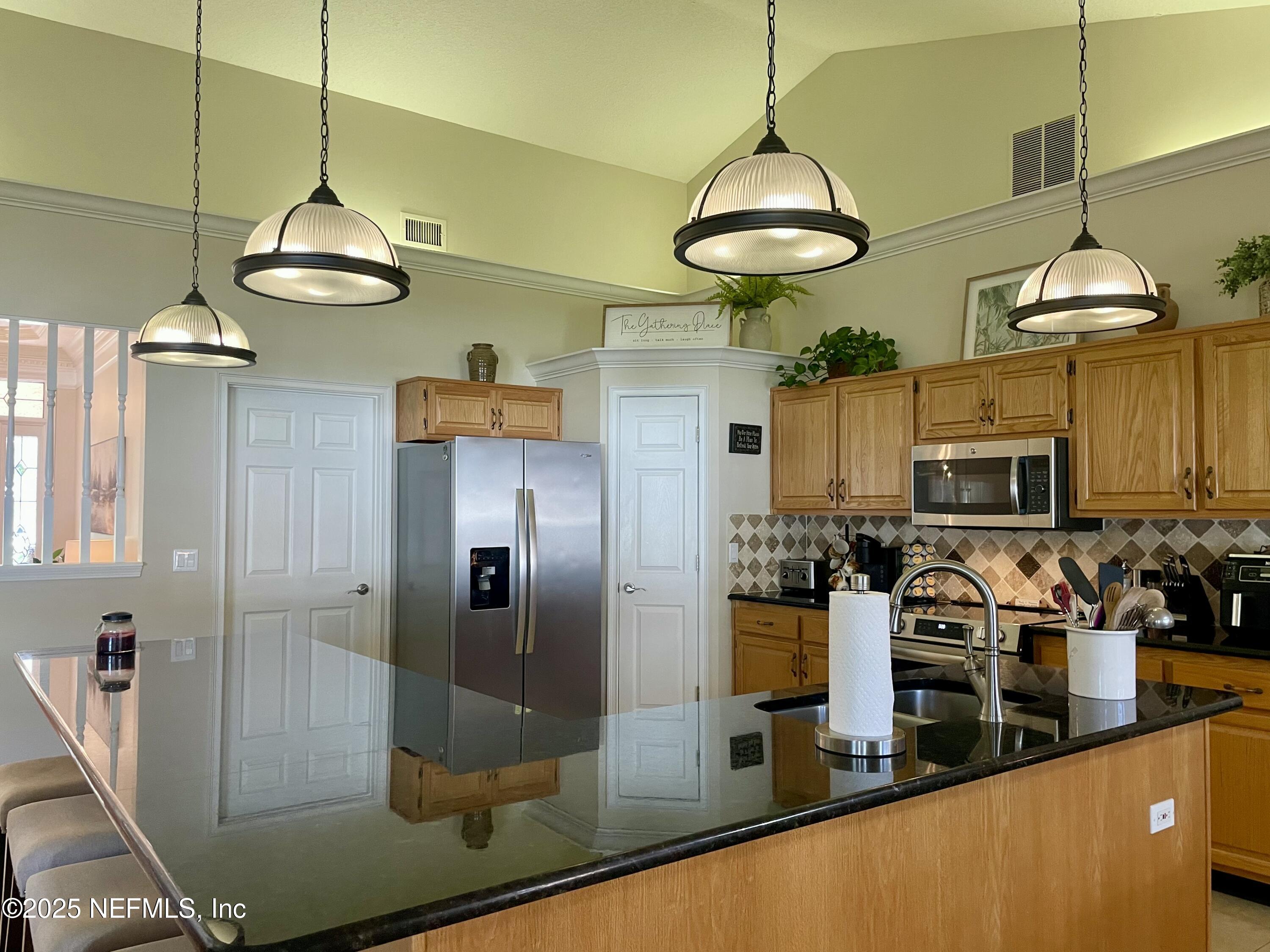 1168 Copper Gate Place Macclenny, FL 32063 - Photo 21 of 44 a kitchen with stainless steel appliances granite countertop a sink a stove and a refrigerator