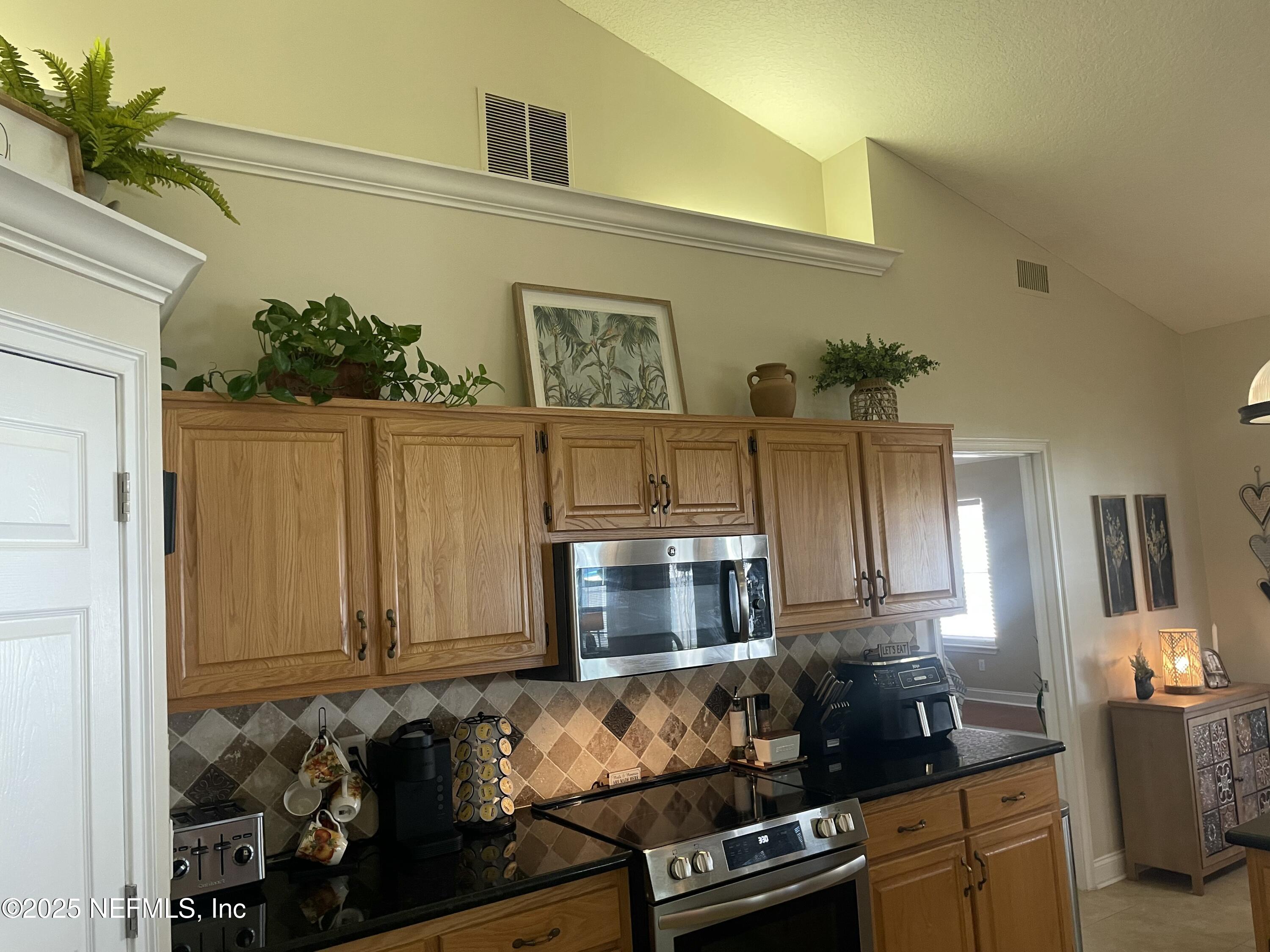 1168 Copper Gate Place Macclenny, FL 32063 - Photo 23 of 44 a kitchen with granite countertop a stove a microwave a sink and cabinets