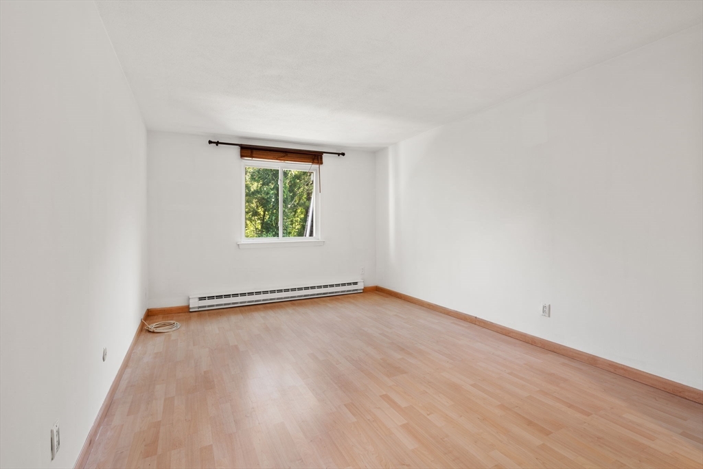 47 Will Drive, Unit 114 Canton, MA 02021 - Photo 17 of 25 an empty room with wooden floor and window