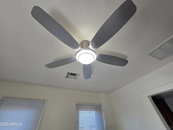 a view of empty room with wooden floor and fan