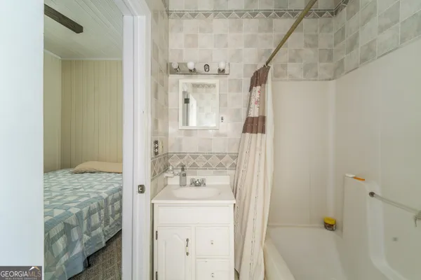 a bathroom with a granite countertop sink a mirror a bathtub and next to a window