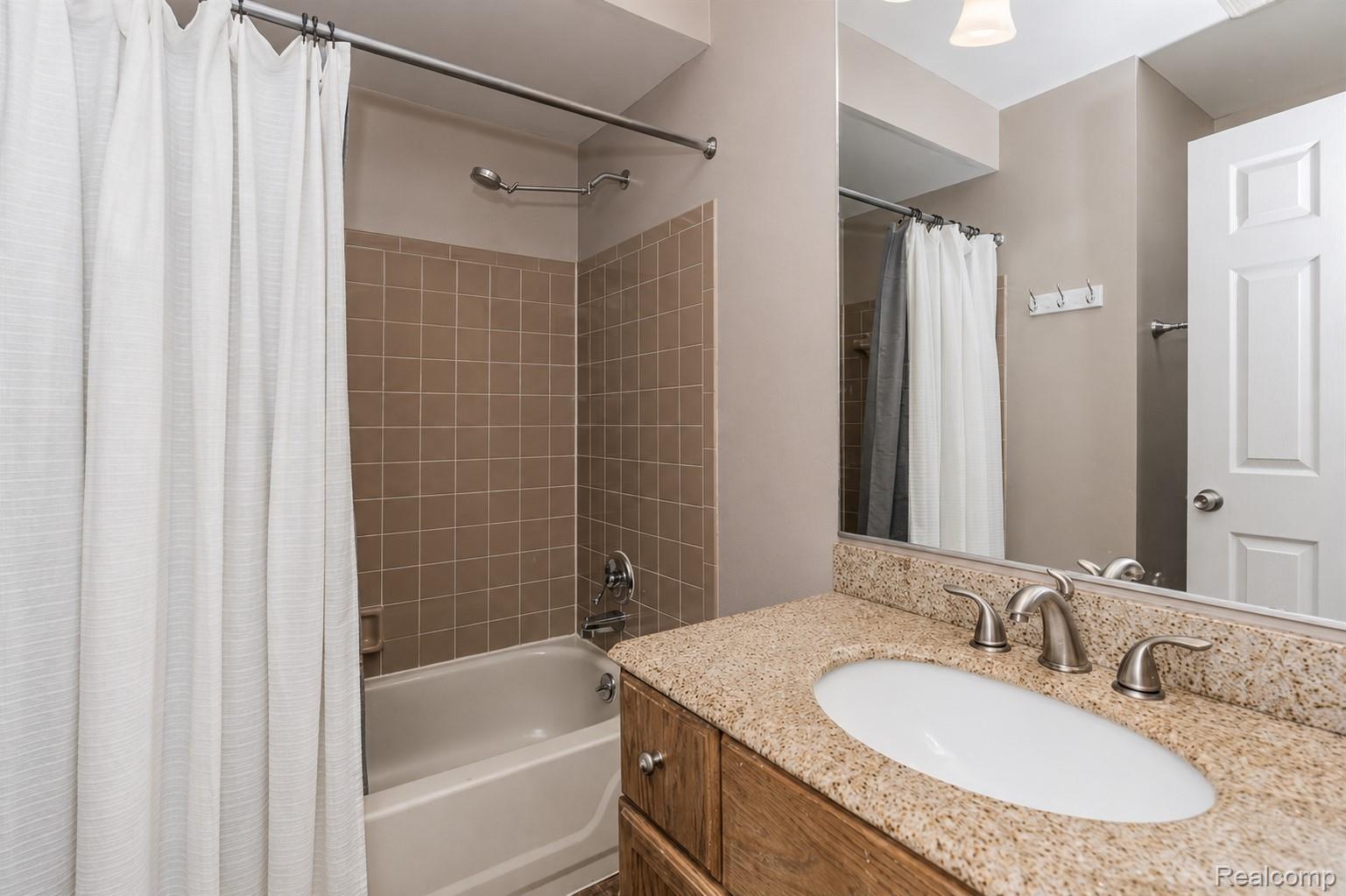 2033 Avonstoke Road Rochester, MI 48307 - Photo 23 of 27 Bathroom featuring a granite-finish countertop with an undermount sink, brushed nickel faucet, and a large mirror
