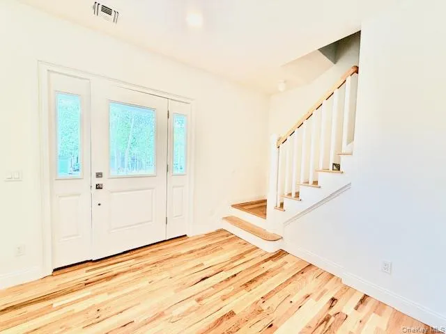 a view of a bedroom with wooden floor and white walls