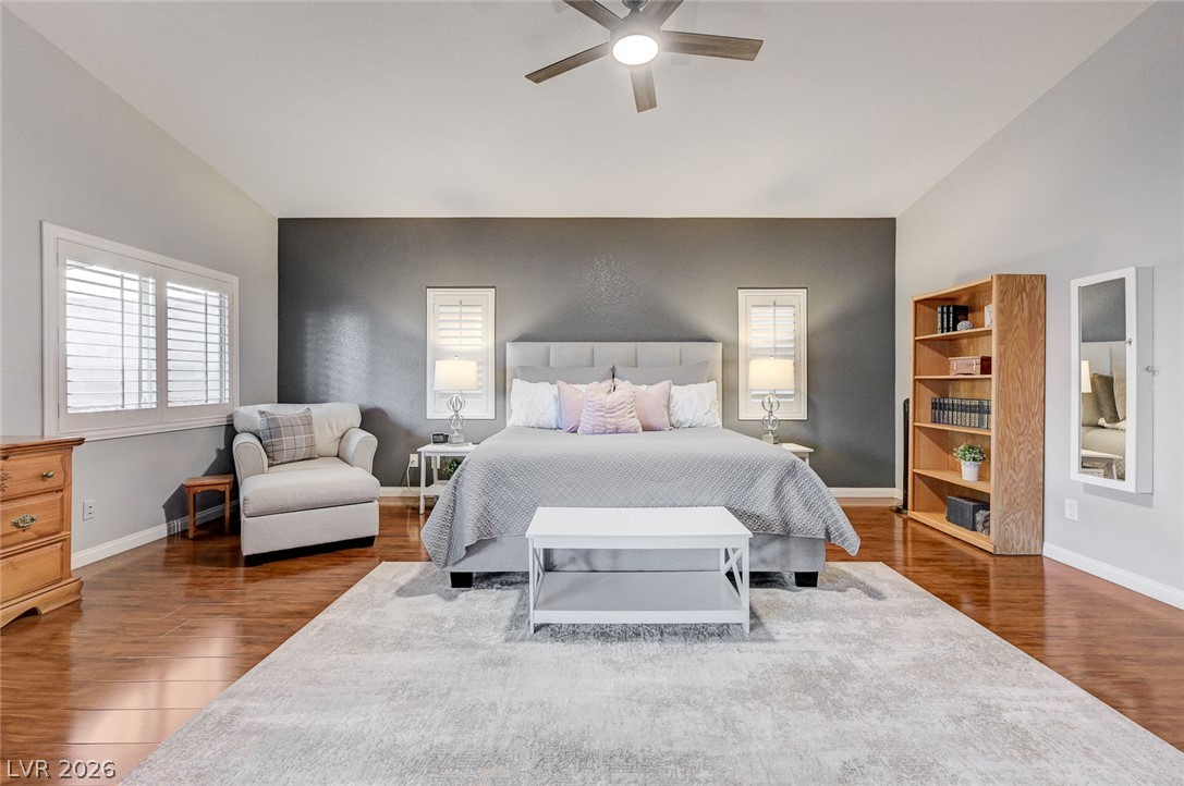 1604 Cattle Ranch Place Henderson, NV 89002 - Photo 34 of 99 Hardwood floors and a vaulted ceiling elevate this primary bedroom's refined aesthetic.