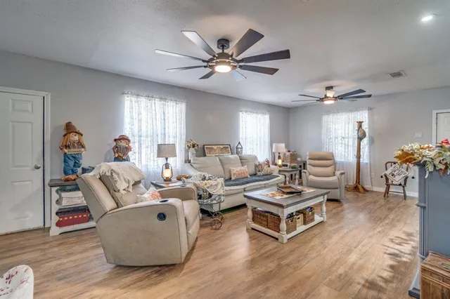 a living room with furniture a chandelier fan and a wooden floor