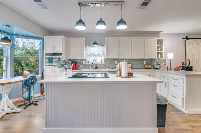 a kitchen with stainless steel appliances granite countertop a stove a sink a refrigerator white cabinets and wooden floor