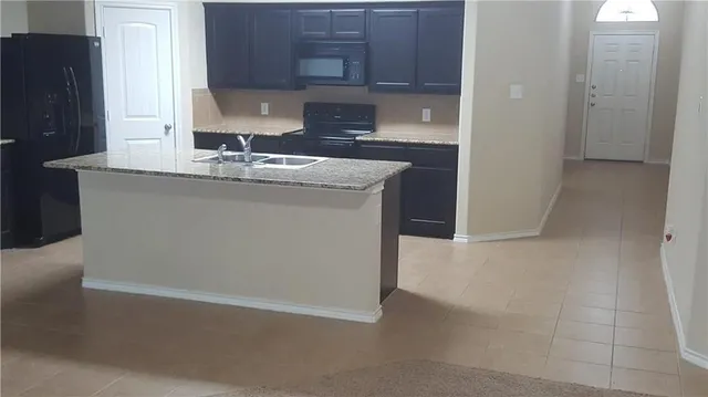 a kitchen with granite countertop a refrigerator and a sink