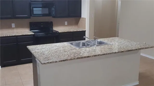 a kitchen with granite countertop a refrigerator and a stove top oven