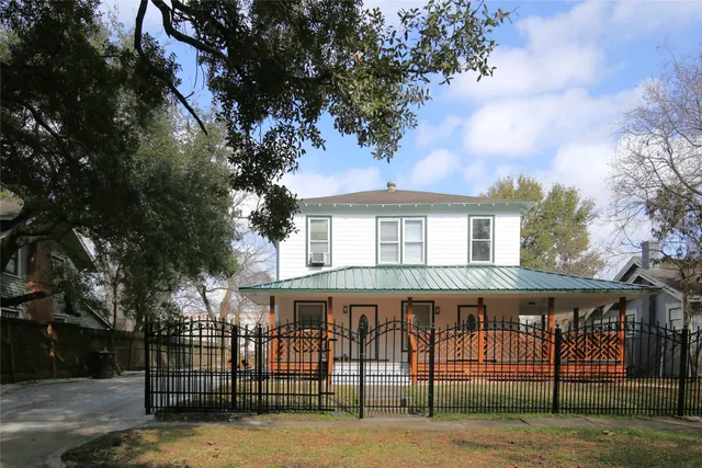 a view of a white house that has a tree in front of it
