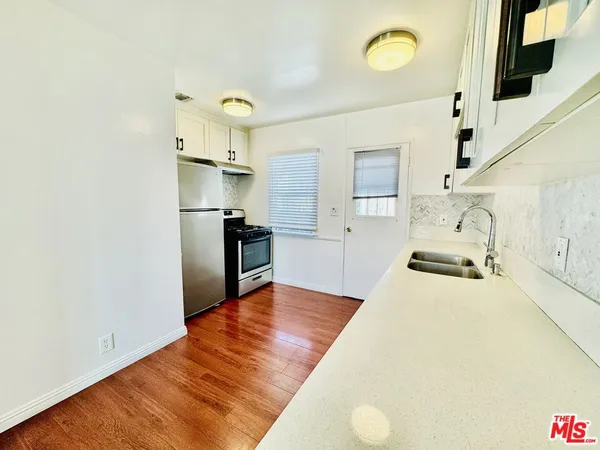 a large white kitchen with wooden floor