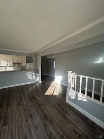 a view of a living room with wooden floor and kitchen view